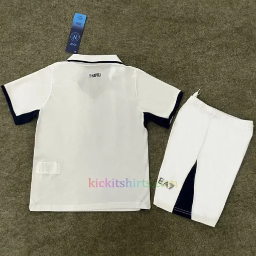 Napoli Away Kit Kids 202425 in white with black accents, featuring a 3D SSC Napoli badge, all-over "N" pattern, and special fingerprint hologram crest at the bottom.