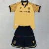 Wrexham AFC 2024/25 kids' third kit in gold, featuring a polo collar, black badge, dragon-scale sleeves, and a tribute detail on the back.